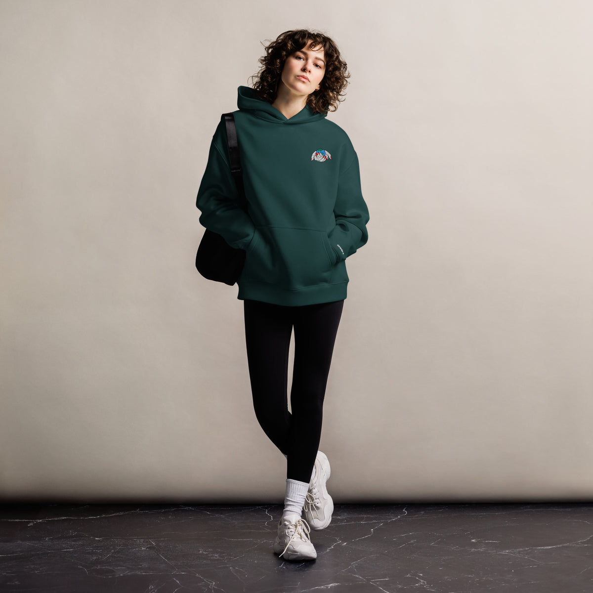 Protect Our Planet unisex oversized hoodie in pine green, front view on a women's lifestyle model (Printful mockup)