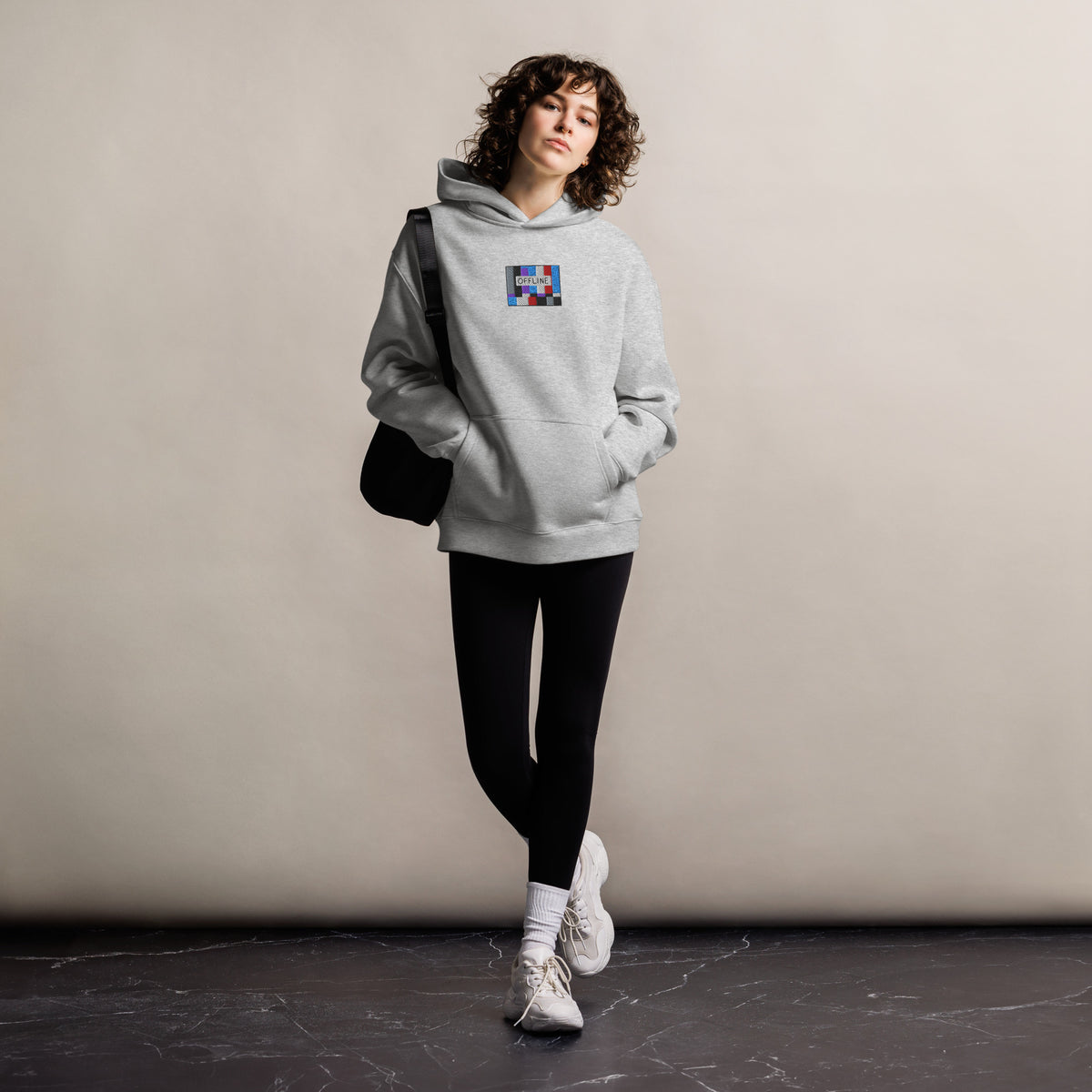 Offline unisex oversized hoodie in athletic heather, front view on a women's lifestyle model (Printful mockup)