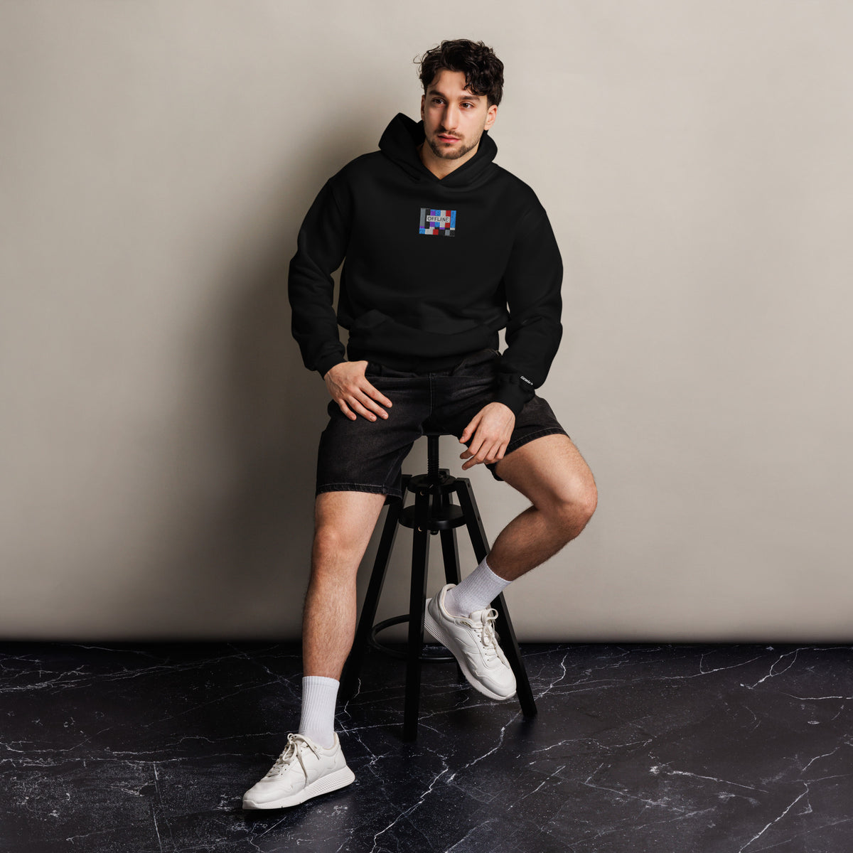 Offline unisex oversized hoodie in black, front view on a men's lifestyle model (Printful mockup)