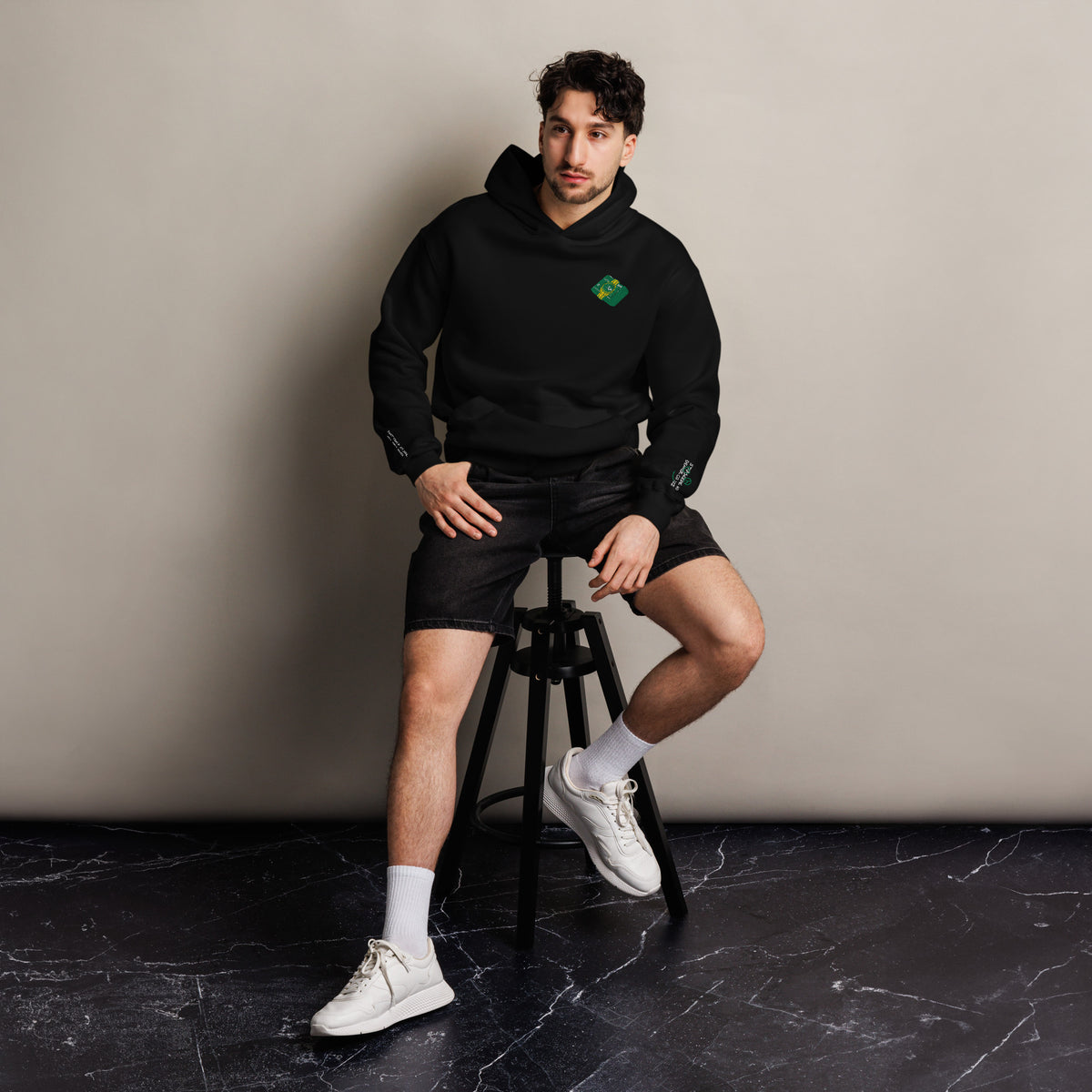 Mickey Money '22 unisex oversized hoodie in black, front view on a men's lifestyle model (Printful mockup)