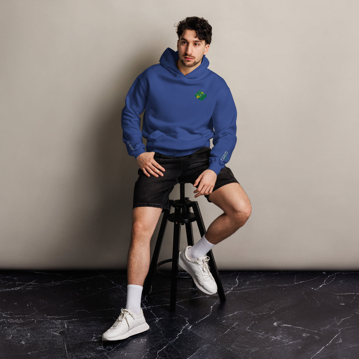 Mickey Money '22 unisex oversized hoodie in cobalt, front view on a men's lifestyle model (Printful mockup)